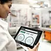 Eine Mitarbeiterin überwacht den Maschinenzustand in der Fertigung per Tablet